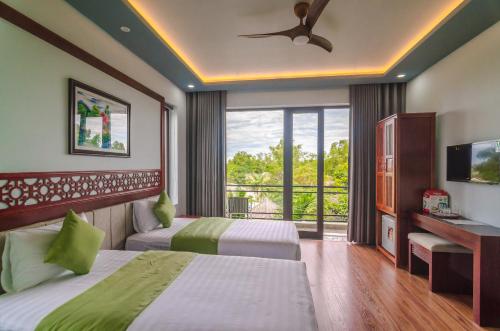 a hotel room with two beds and a balcony at Tue Tam Garden Villa in Hoi An