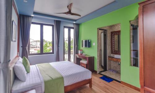 a bedroom with green walls and a bed with a fireplace at Tue Tam Garden Villa in Hoi An