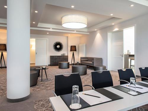 a meeting room with tables and chairs and a couch at Victor's Residenz-Hotel Teistungenburg in Teistungen