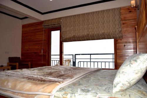 - une chambre avec un grand lit et une grande fenêtre dans l'établissement Hilla Apartments Nathia Gali, à Abbottābād