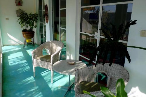 a porch with two chairs and a table and a plant at Casa de la Luz - Studio Apartment in Tlacotalpan