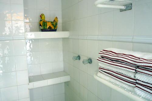 a white tiled bathroom with a shower and towels at Casa de la Luz - Studio Apartment in Tlacotalpan