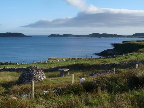 a field with a fence and a body of water at Skellig Cottages in Ballinskelligs