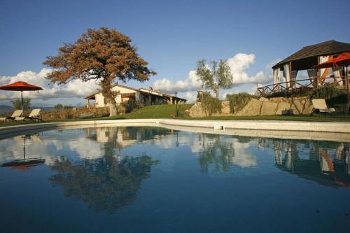 una grande piscina d'acqua di fronte a una casa di Bio Agriturismo La Bell'Antiglia a Montemerano