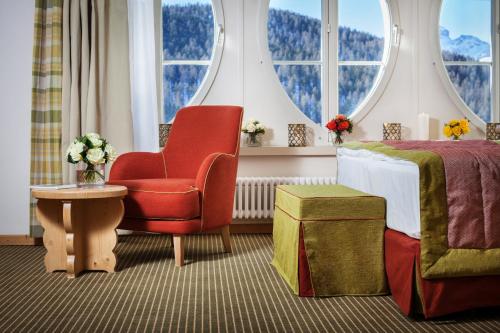 a hotel room with a bed and a chair and windows at Schloss Hotel & Spa Pontresina in Pontresina