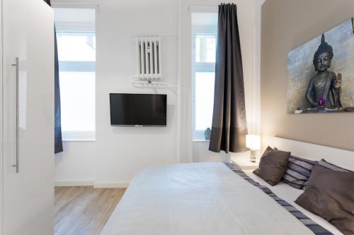 een witte slaapkamer met een bed en een televisie bij GreatStay - Düsseldorferstr. 48 in Berlijn