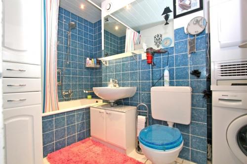 a blue tiled bathroom with a toilet and a sink at Private Rooms Laatzen in Hannover