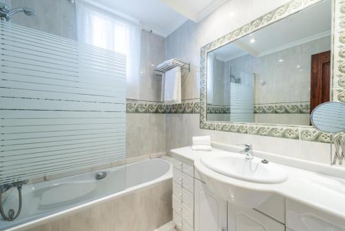 a white bathroom with a tub and a sink and a bath tubermott at Apartamento SAMU 1 in Cala Ratjada