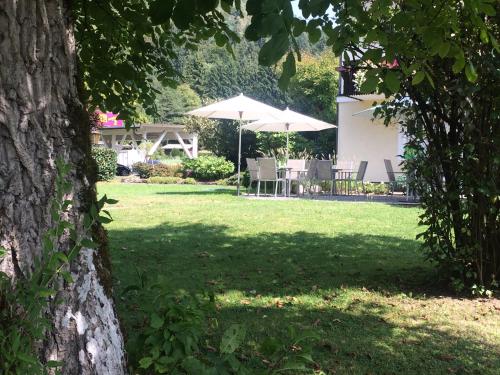 a yard with a table and chairs and umbrellas at Hotel Garni Wurzer in Velden am Wörthersee