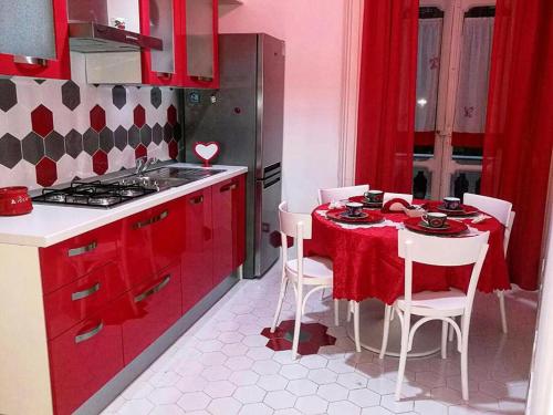 ナポリにあるB&B Resta Cu Mmeのキッチン(赤いキャビネット、テーブル、椅子付)