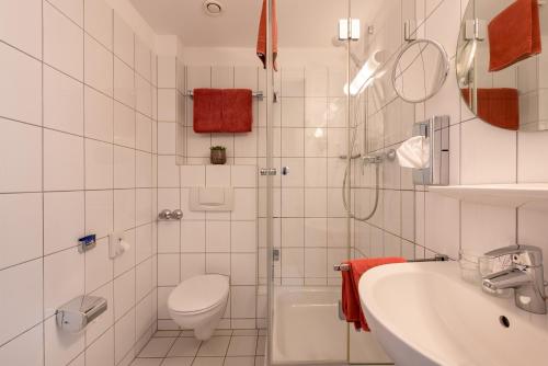 Baño blanco con aseo y lavamanos en Hotel Conti Am Hauptbahnhof en Münster