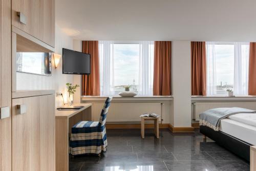 a hotel room with a bed and a desk with a television at Hotel Conti Am Hauptbahnhof in Münster