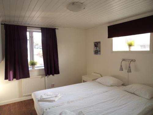 a bedroom with a white bed and two windows at Gamla Bryggeriet Bed & Breakfast in Köpingsvik