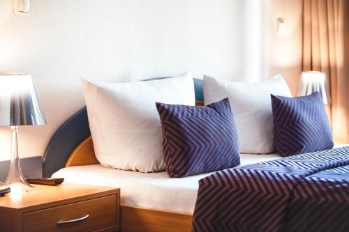 a bed with blue and white pillows on it at Hotel Ambiente Berlin City in Berlin