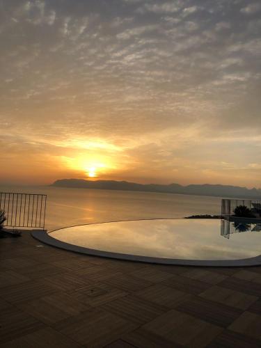 a swimming pool with the sunset in the background at Hotel Antica Cascina Del Golfo in Scopello