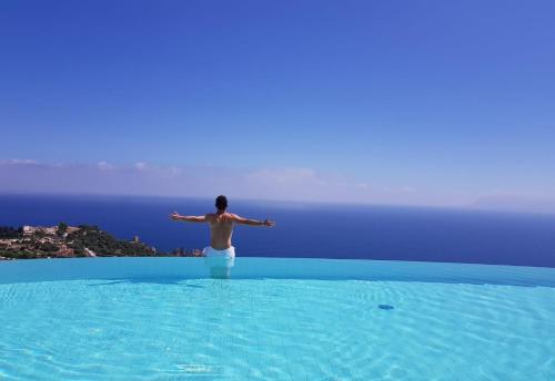 a man standing on the edge of a pool in the water at Hotel Antica Cascina Del Golfo in Scopello