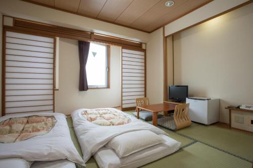 Kama o mga kama sa kuwarto sa Hotel Sunroute Aomori