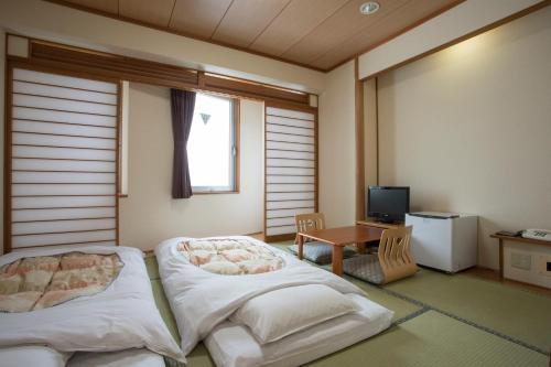 a room with a bed and a table and a window at Hotel Sunroute Aomori in Aomori