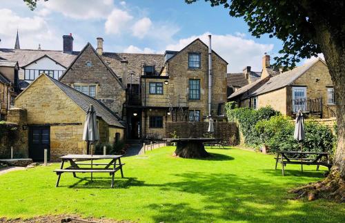 ein großes Steingebäude mit Picknicktischen im Gras in der Unterkunft The Stag at Stow in Stow on the Wold