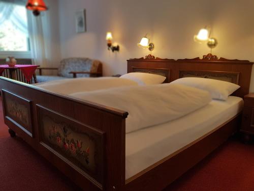 a bedroom with a large bed with white sheets at Hotel Landhaus Sonnenhof in Todtnau