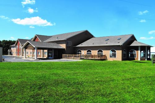 a large building with a green field in front of it at AmericInn by Wyndham Jefferson in Jefferson