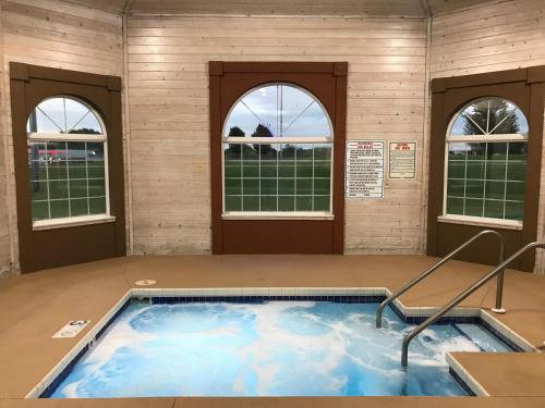 a hot tub in a room with three windows at AmericInn by Wyndham Jefferson in Jefferson