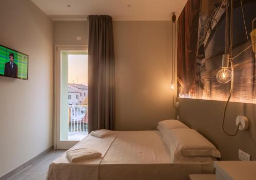 a small bedroom with a bed and a window at porto canale b & b in Cesenatico