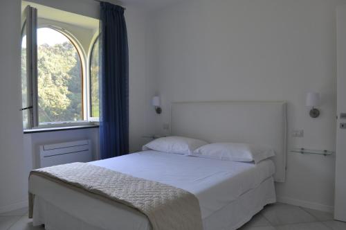 a white bedroom with a bed and a window at Via Paradiso in Amalfi