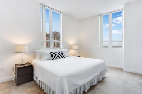 a white bedroom with a bed and two windows at Dadeland Towers by Miami Vacations in South Miami