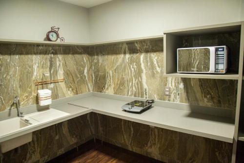 a kitchen with a sink and a microwave at Jockey Class Hotel in Teresina