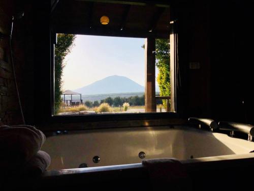 a bath tub with a view of a mountain through a window at Noach Batavor in Kefar Qish