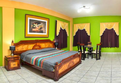 伊卡的住宿－Hotel Colon Plaza，一间卧室设有绿色的墙壁、一张床和一张桌子