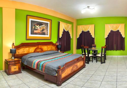 a bedroom with green walls and a bed and a table at Hotel Colon Plaza in Ica