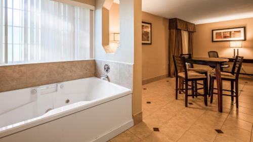 a bathroom with a tub and a table with chairs at Best Western Plus Prairie Inn in Albany