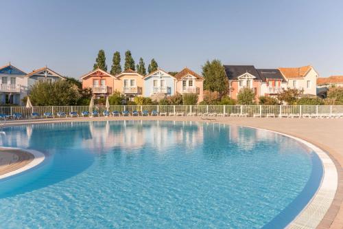 uma grande piscina com casas ao fundo em Résidence Pierre & Vacances Le Domaine de Bourgenay em Talmont