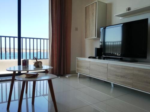 uma sala de estar com uma televisão de ecrã plano e uma mesa em No8 @ Seabreeze Court em Mellieħa