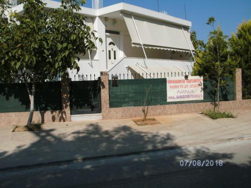 a white house with a sign in front of it at Nina Rooms (apartments) in Artemida