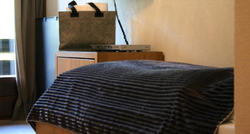 a bed with a blue blanket and a tote bag at MONTAFONLodge in Gaschurn