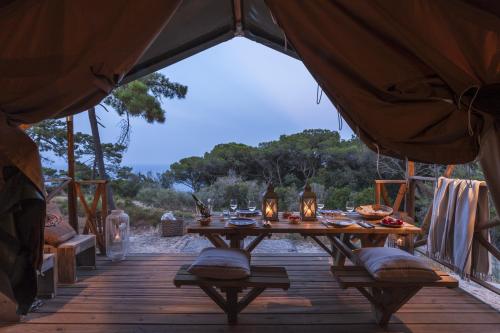 a wooden deck with a table in a tent at Tenuta Delle Ripalte in Capoliveri