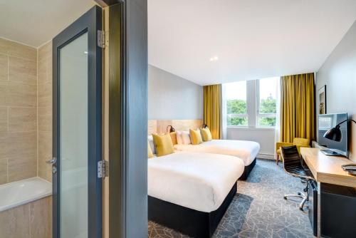 a hotel room with two beds and a desk at Apex Grassmarket Hotel in Edinburgh