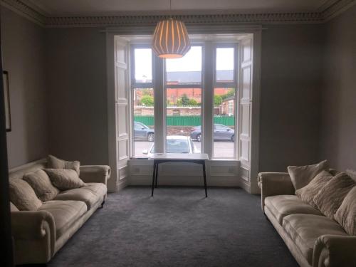 a living room with two couches and a large window at Aberdour Guest House in Dumfries