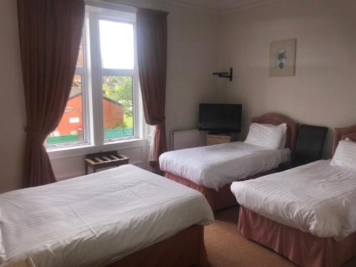 a hotel room with two beds and a window at Aberdour Guest House in Dumfries