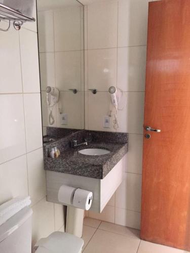 a bathroom with a sink and a mirror and a toilet at Flat Beira-Mar Blue Sunset in João Pessoa