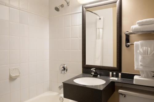 a bathroom with a sink and a tub and a mirror at Days Inn by Wyndham Victoria On The Harbour in Victoria