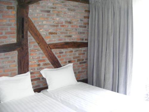 a bedroom with two beds and a brick wall at Amosa Liège City Centre Apart Gerardrie 23 in Liège