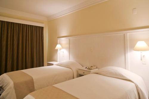a hotel room with two beds and a phone at Vitória Hotel Convention Indaiatuba in Indaiatuba