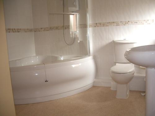 a bathroom with a toilet and a tub and a sink at Compton House in Ashbourne