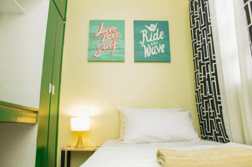 a bedroom with a bed with two pictures on the wall at Nomads MNL Backpackers Homestay - near Airport in Manila