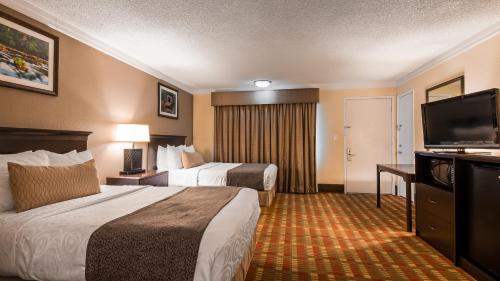 a hotel room with two beds and a flat screen tv at Best Western Garden Villa Inn in Roseburg