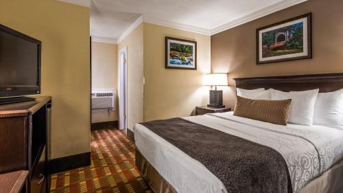 a hotel room with a bed and a flat screen tv at Best Western Garden Villa Inn in Roseburg